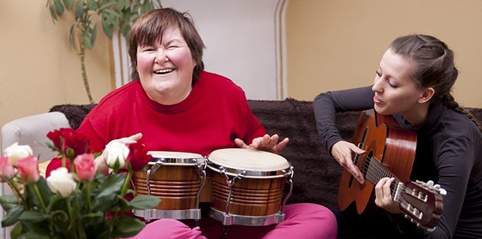 Verzorger speelt muziek samen met een verstandelijk gehandicapte vrouw