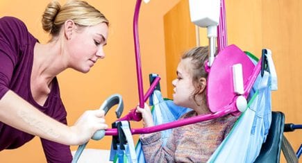 Verzorger helpt jong gehandicapt kindje